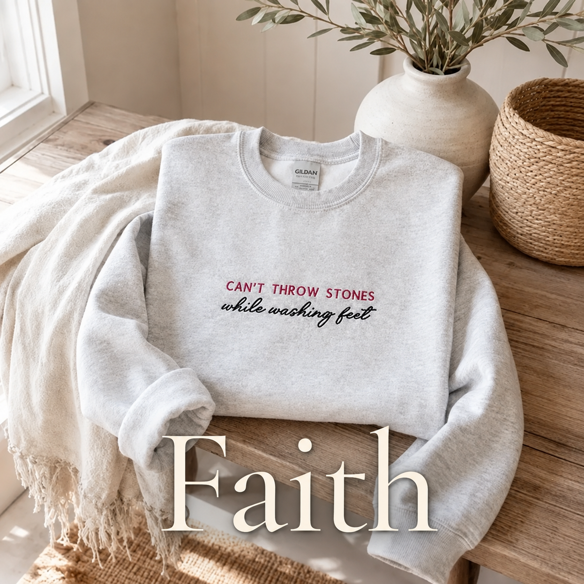 Ash grey crewneck shirt displaying saying " can't throw stones while washing feet" saying in Red and black thread. 